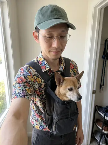 Angelo, AI character: his small Daly City apartment by the front door before a slow Sunday walk, shoe rack and leash hook behind him