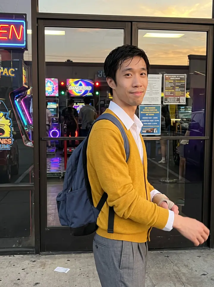 Ian, AI character: outside the Gardena arcade just after practice, the dance-pad machines glowing behind the glass doors