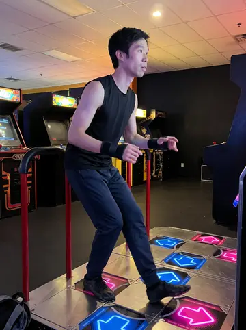 Ian, AI character: inside the Gardena arcade on a weekend night, standing on the dance-pad rhythm game platform