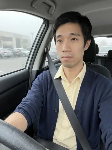 Ian, AI character: parked in his compact car before work in a Torrance office lot on a grey morning