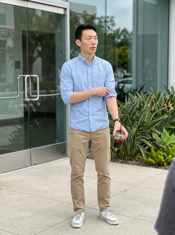 Robert, AI character: outside an Irvine office building during a coffee run, glass doors and a planter strip behind him