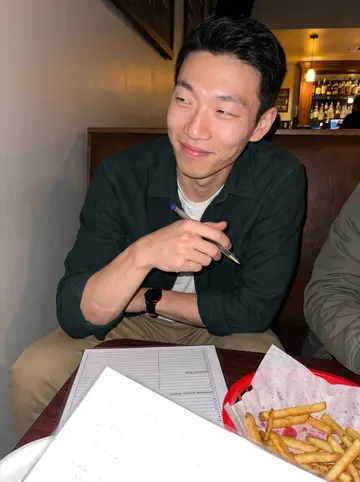 Robert, AI character: a Wednesday pub trivia table in Costa Mesa, laminated answer sheets and half-finished fries on the table