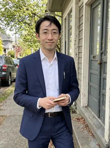 Yuki, AI character: a quiet Capitol Hill sidewalk in Seattle after a house showing, old painted front doors and spring trees…