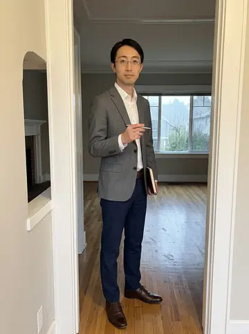 Yuki, AI character: an empty Queen Anne open house with hardwood floors, a narrow hall, and rain-dark windows behind him