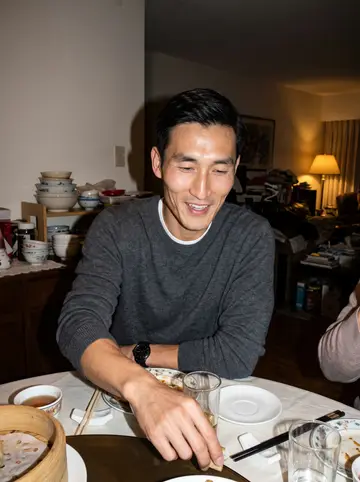 Alvin, AI character: his grandmother's dining room during a Sunday family meal, bamboo steamers and tea cups on the round table