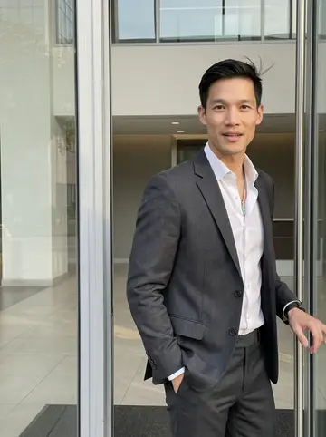 Khoa, AI character: outside a downtown Houston office tower after market close, glass doors and a strip of spring sun behind him
