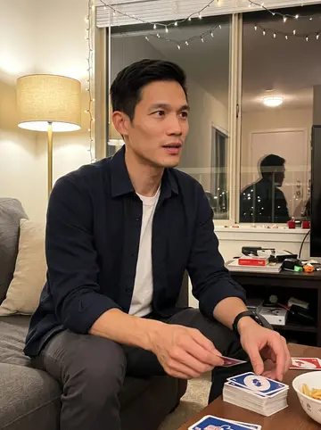 Khoa, AI character: a friend's apartment during a quiet holiday board-game night, string lights along the window and cards on…