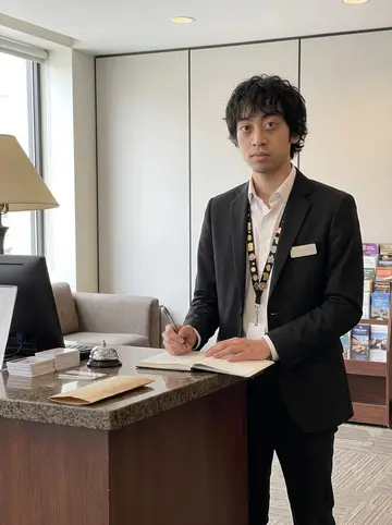 Jiahao, AI character: behind the front desk of a small downtown San Francisco hotel during a quiet afternoon handover