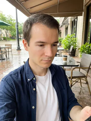 Mathieu, AI character: a small Houston cafe patio after summer rain, wet pavement and a coffee cup on the table edge