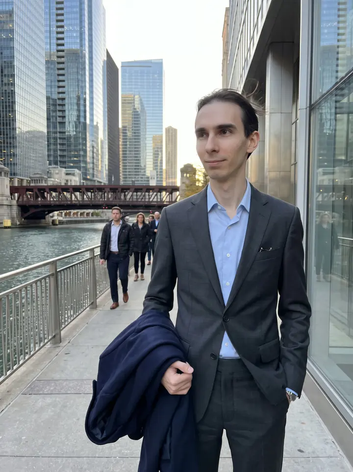 Benoît, AI character: Chicago Riverwalk near the glass office towers after work, amber autumn light on the buildings