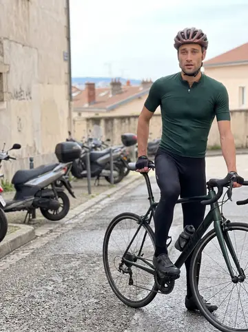 Antonin, AI character: near the top of the Croix-Rousse hill on a Sunday morning, road bike beside him and Lyon rooftops far below