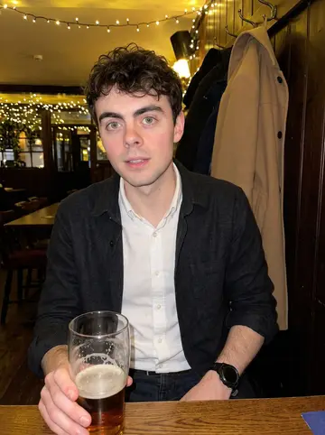 Gerard, AI character: his sister Aoife's engagement dinner in a busy Dublin pub, fairy lights and coats hanging behind the table