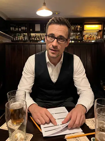 Seamus, AI character: his regular Thursday pub quiz table in a warm Edinburgh pub, dark wood booths and quiz papers on the table