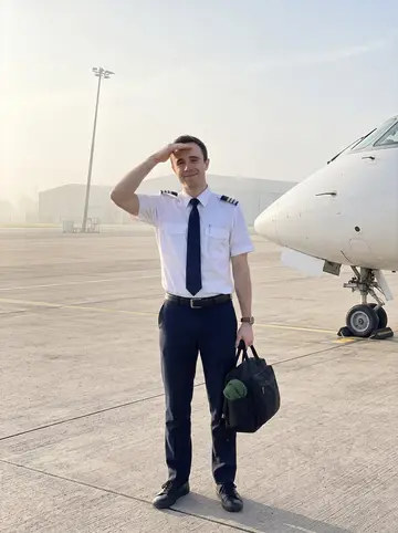Padraig, AI character: a Dublin Airport jet bridge before an early regional flight, aircraft door and grey apron visible behind him