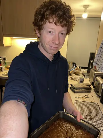 Douglas, AI character: his flat kitchen in Edinburgh late at night, sticky toffee pudding cooling in a baking tin on the counter