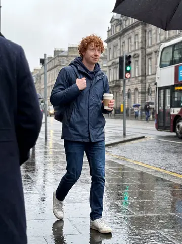Douglas, AI character: wet pavement near Waverley Station on a rainy spring morning, buses and grey stone buildings in the background