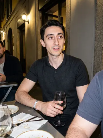 Leone, AI character: outside a narrow wine bar in Brera after dinner with two colleagues cropped mostly out of frame