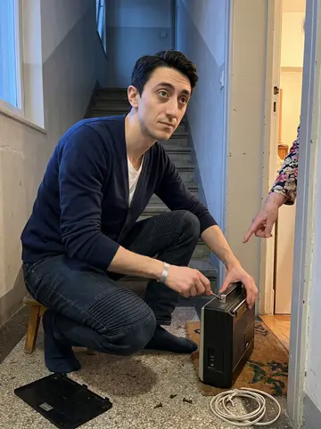Leone, AI character: the stair landing outside Signora Abate's apartment door, with an old radio open on a small stool