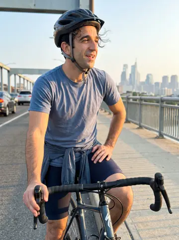 Amedeo, AI character: the South Street Bridge on a warm summer Sunday evening, Center City Philadelphia hazy behind him