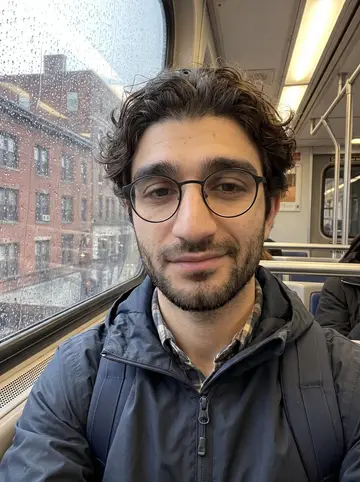 Giancarlo, AI character: inside an MBTA train on a rainy Boston morning, wet window and blurred brick buildings behind him