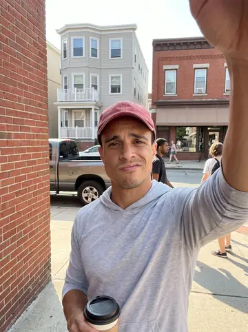Rafael, AI character: the second-floor back porch of his triple-decker in Providence, rows of white buckets holding hot pepper…