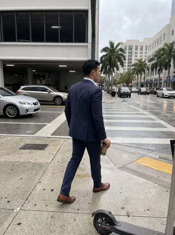 Tomás, AI character: a downtown Miami sidewalk outside a parking garage, damp pavement, traffic reflected in dark windows
