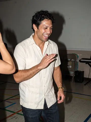 Jorge, AI character: a small salsa class in a Miami community center, music equipment and folding chairs behind him