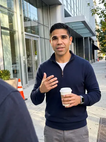 Guillermo, AI character: outside a Midtown Atlanta office building during a late afternoon coffee break