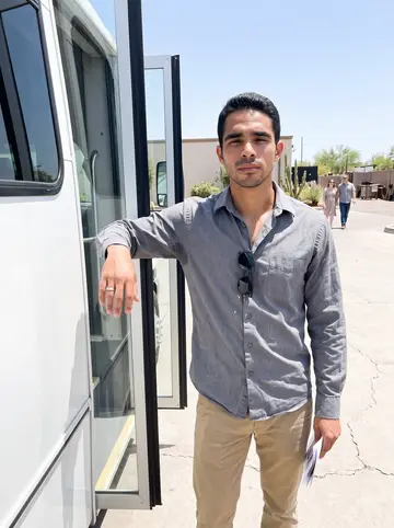 Alejandro, AI character: the venue parking lot beside a white event shuttle used for touring couples around the property