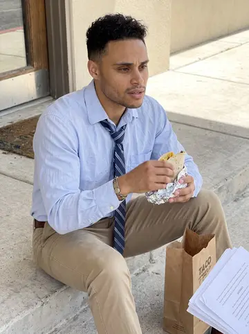 Wilfredo, AI character: outside a small San Antonio law office during lunch, sitting on the concrete steps beside a paper taco bag…