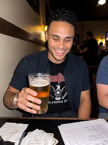 Wilfredo, AI character: a crowded San Antonio pub on Wednesday trivia night with his team score sheet on the table
