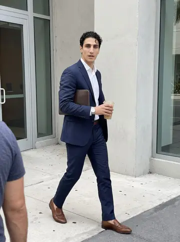 Giovanni, AI character: the sidewalk outside his downtown Miami office building during a short coffee run between meetings