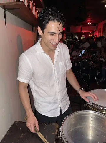Giovanni, AI character: a packed Little Havana salsa bar on a Sunday night, beside the timbales between sets