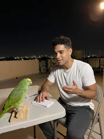 Yosvany, AI character: the rooftop of his Hialeah apartment building after midnight, low skyline lights behind him, Celia the…