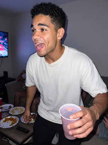 Yosvany, AI character: his cousin's living room during a Miami Heat game watch party, couch crowded just out of frame, TV glow…