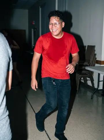 Erick, AI character: Thursday bachata night in a church hall in Providence, polished floor and stacked chairs in the background