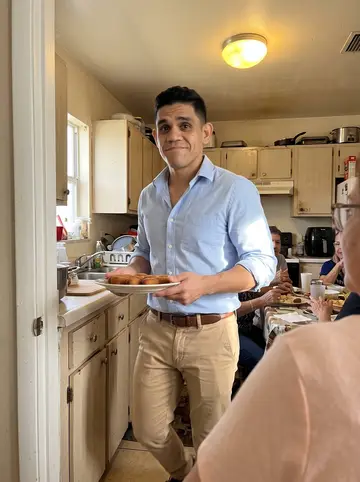 Yadiel, AI character: his abuela's Hialeah apartment kitchen during Sunday croquetas, with relatives partly cropped around the table