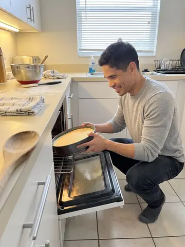 Yordan, AI character: his apartment kitchen in Hialeah, cheesecake pan too large for the small oven, mixing bowls on the counter