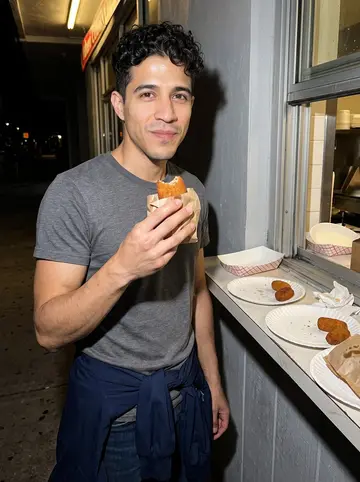Ruairí, AI character: a busy Cuban ventanita counter in Miami at night, paper plates and croquetas on the narrow ledge