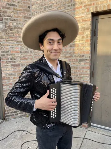 Dominik, AI character: outside a Chicago banquet hall before a Saturday wedding gig, standing near the side entrance with his…