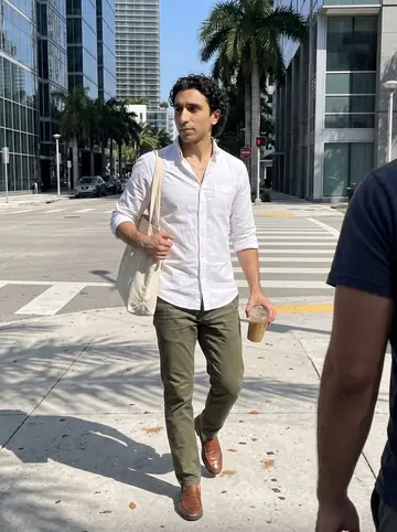 Denis, AI character: a bright Brickell sidewalk on a work morning, glass office towers and a crosswalk behind him