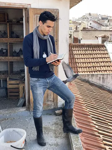 Telmo, AI character: his late grandfather's rooftop pigeon loft in Lisbon, wooden doors, wire cages, clay roof tiles and city…