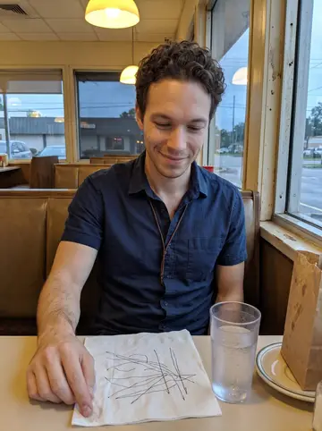 Aurelio, AI character: a small Tampa diner booth after work, a napkin with drainage sketches and a bag of roadside fruit on the table