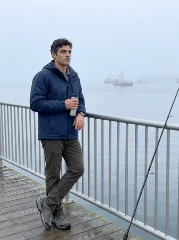 Cândido, AI character: New Bedford pier early in the morning, fog over the water and fishing lines along the railing
