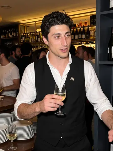 Mikel, AI character: crowded pintxos night at the restaurant bar, late after the rush, plates and small wine glasses around him