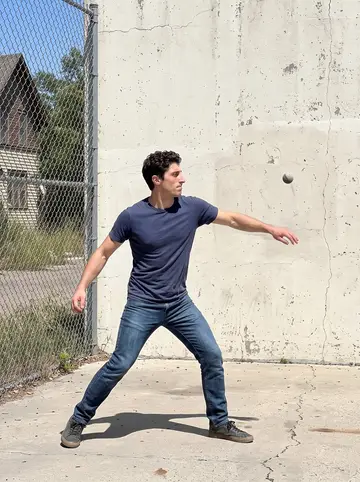 Mikel, AI character: handball wall behind the old Basque boarding house in Boise, playing pelota on a Sunday afternoon