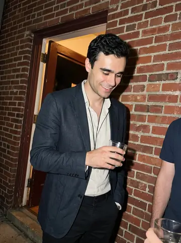 Mateus, AI character: outside a small fado night in Newark, friends cropped around him near a brick wall and open doorway