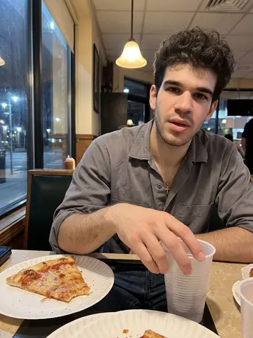 Artur, AI character: a casual Columbus pizza place booth after work, paper plates and a half-finished slice on the table
