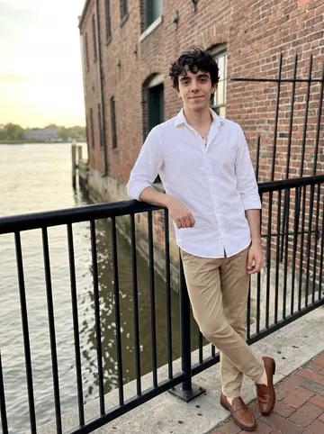 Álvaro, AI character: Savannah riverfront near old brick warehouses, leaning against a black iron railing after work