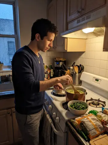 Luís, AI character: his cousin's tiny Newark apartment kitchen on a rainy spring evening, a pot of caldo verde on the stove…
